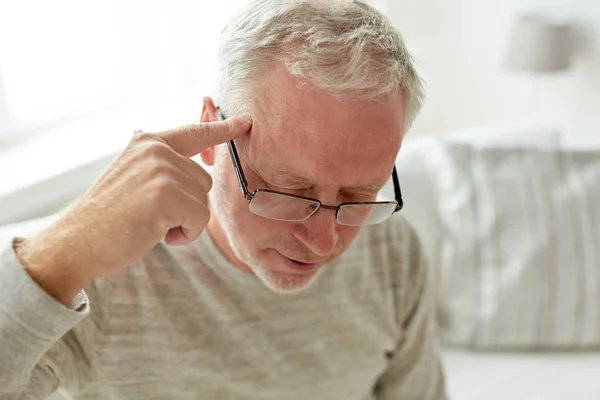 Hombre mayor que sufre de dolor de cabeza en casa —  Fotos de Stock