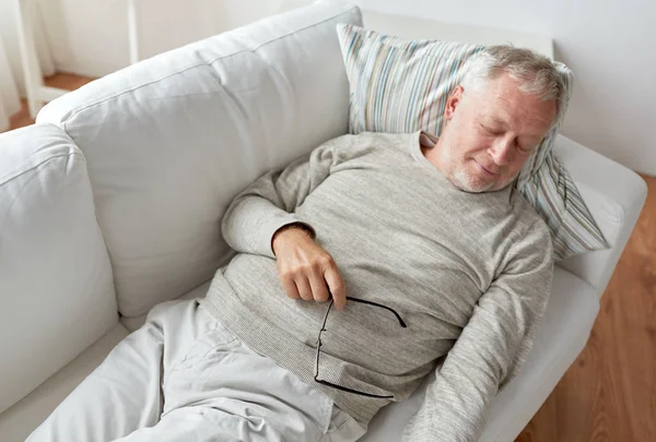 Старший мужчина спит на диване дома — стоковое фото