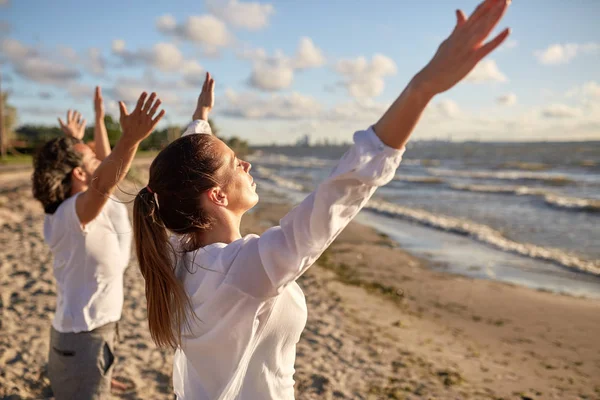 Grupp av människor att göra yoga eller mediterar på stranden — Stockfoto