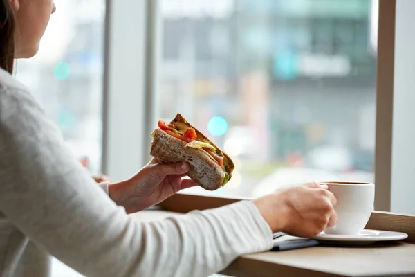 Mujer comiendo sándwich y tomando café en la cafetería —  Fotos de Stock