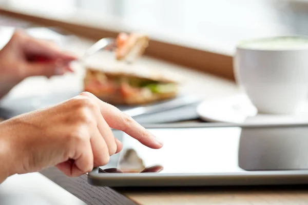 Mujer con tableta pc y panini sándwich en la cafetería — Foto de Stock