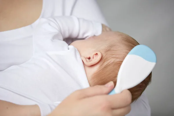 Nahaufnahme einer Mutter, die neugeborene Babyhaare bürstet — Stockfoto