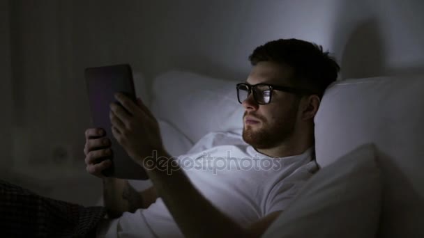Человек в очках и планшетных ПК в постели ночью — стоковое видео