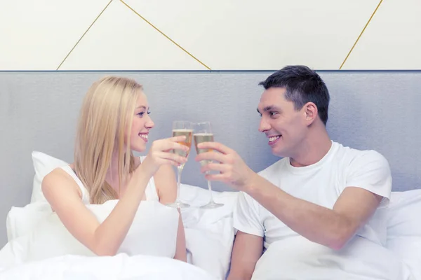 Smiling couple with champagne glasses in bed — Stock Photo, Image