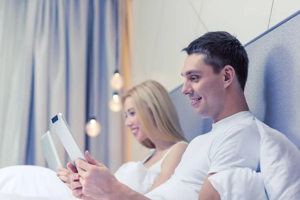 Pareja sonriente en la cama con tabletas PC —  Fotos de Stock