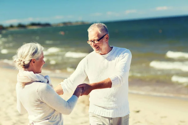 Happy senior couple holding hands on summer beach — Stock Photo, Image