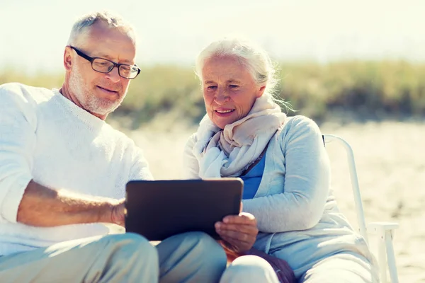 Felice coppia anziana con tablet pc sulla spiaggia estiva — Foto Stock