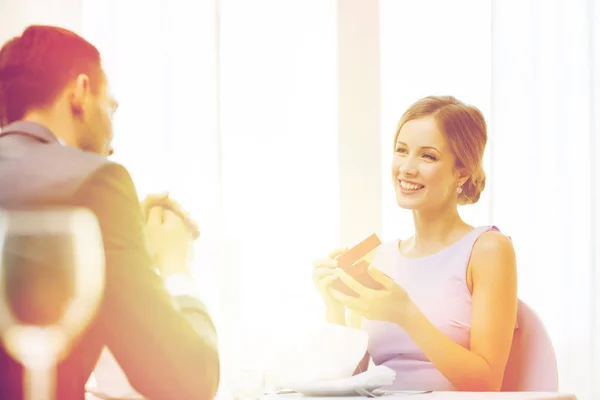 Excited young woman looking at boyfriend with box — Stock Photo, Image