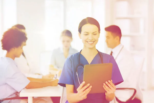 Zufriedener Arzt mit Tablet-PC über Team in Klinik — Stockfoto