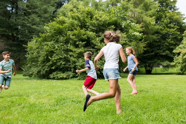Группа счастливых детей или друзей, играющих на открытом воздухе — стоковое фото