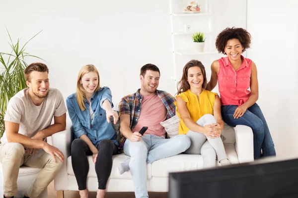 Glada vänner med remote vaktande tv hemma — Stockfoto