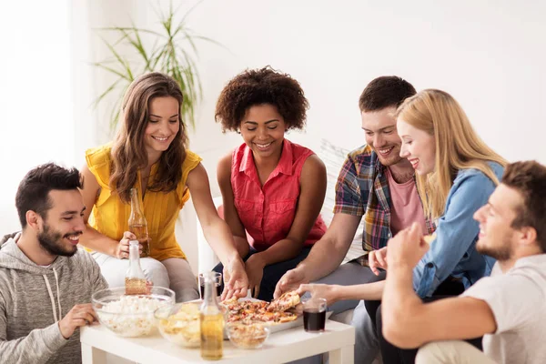 Amici felici con bevande mangiare pizza a casa — Foto Stock