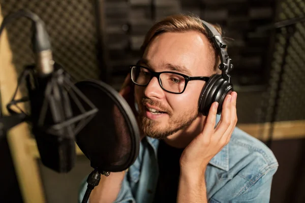 Uomo con le cuffie che canta in studio di registrazione — Foto Stock
