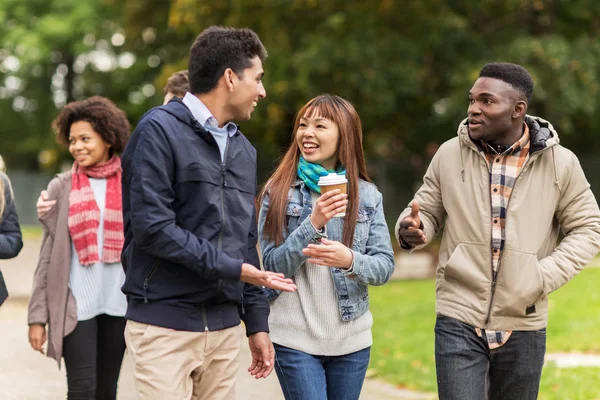 Gelukkige vrienden wandelen langs het herfstpark — Stockfoto