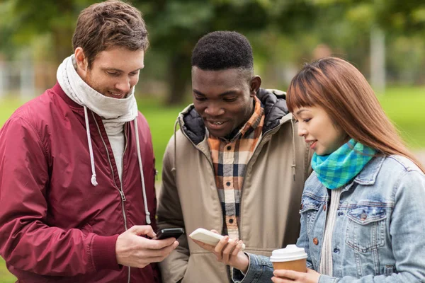 Gelukkige vrienden met smartphone en koffie outdoors — Stockfoto