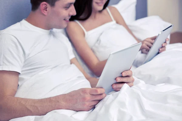Lachende paar in bed met tablet pc-computers — Stockfoto