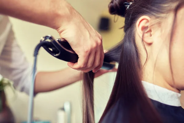 Stilista con ferro raddrizzando capelli a salone — Foto Stock