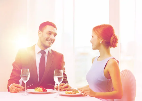 Sonriente pareja comiendo plato principal en restaurante — Foto de Stock