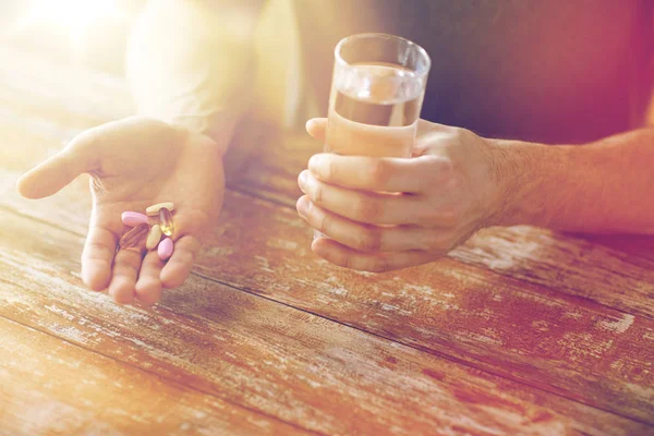 Close up van mannelijke handen met pillen en water — Stockfoto