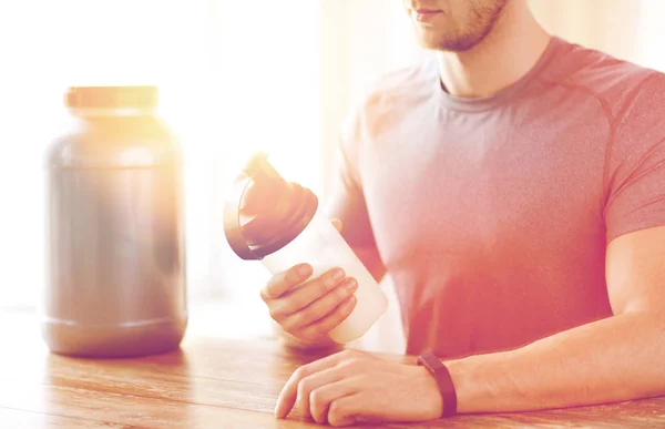 Närbild på mannen med protein shake flaska och burk — Stockfoto