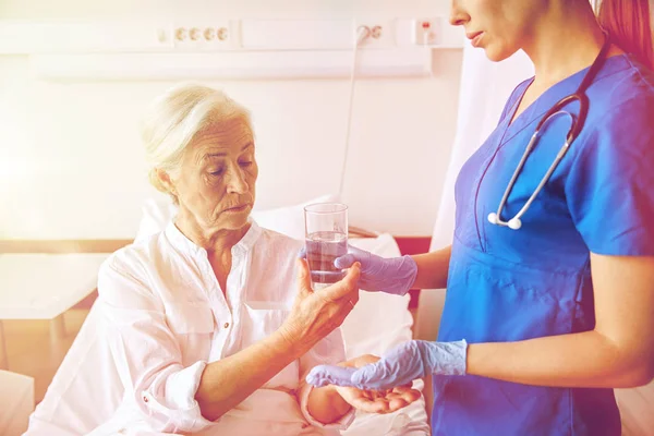 Enfermeira dando remédio para a mulher idosa no hospital — Fotografia de Stock