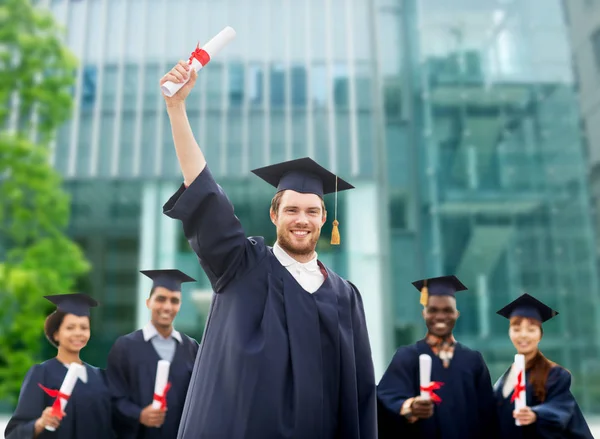 Glada studenter i murbruk styrelser med diplom — Stockfoto