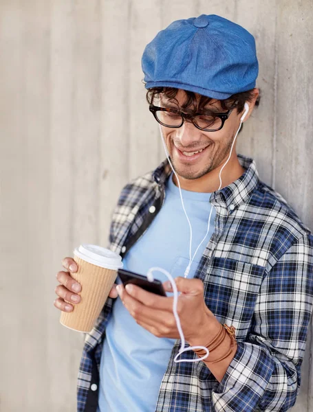 Man med hörlurar och smartphone dricka kaffe — Stockfoto