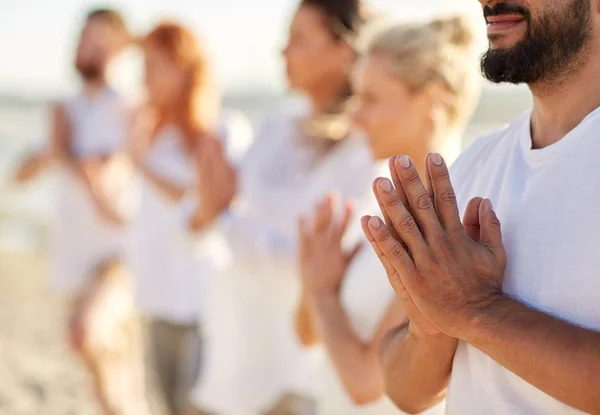 Grupo de personas haciendo yoga o meditando en la playa —  Fotos de Stock