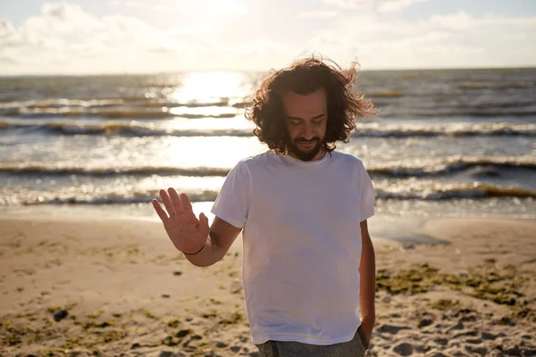 Gelukkig man in wit t-shirt op strand over zee — Stockfoto