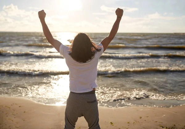 Man met tiseerde vuist op strand — Stockfoto