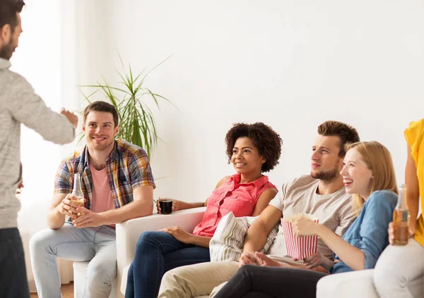 Amigos con palomitas de maíz y bebidas hablando en casa — Foto de Stock