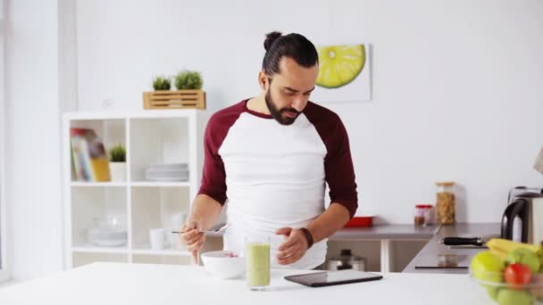 Man with tablet pc eating breakfast at home — Stock Video