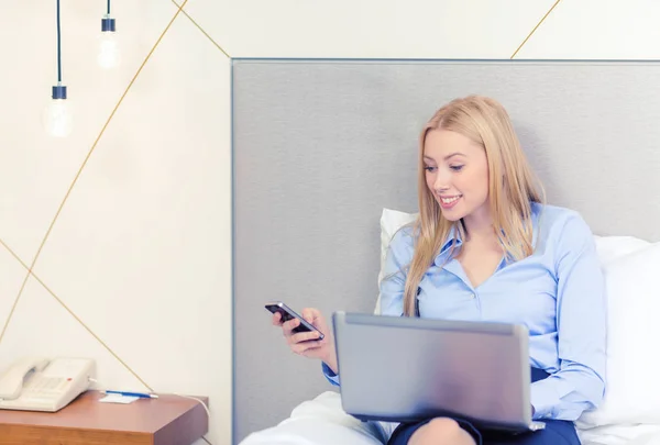 Happy businesswoman with smartphone in hotel room — Stock Photo, Image