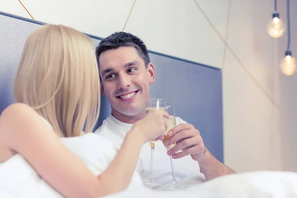 Uśmiechający się para z szampana kieliszki w łóżku — Zdjęcie stockowe