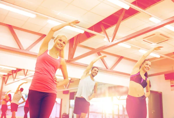 Groep glimlachende mensen die zich uitstrekt in de sportschool — Stockfoto