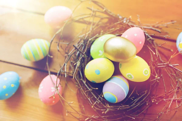 Close up of colored easter eggs in nest on wood — Stock Photo, Image