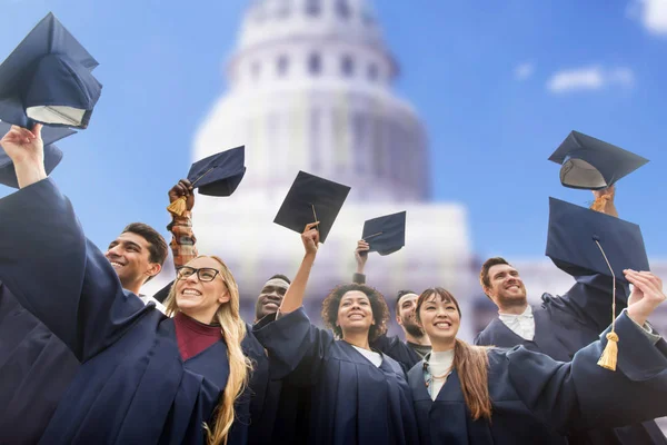 Happy students or bachelors waving mortar boards — Stock Photo, Image