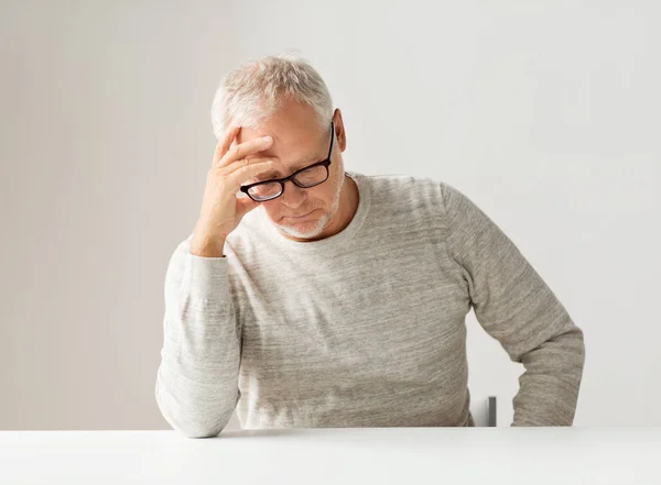 Triste hombre mayor sentado en la mesa — Foto de Stock