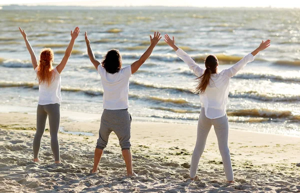 Grupp av människor att göra yoga eller mediterar på stranden — Stockfoto