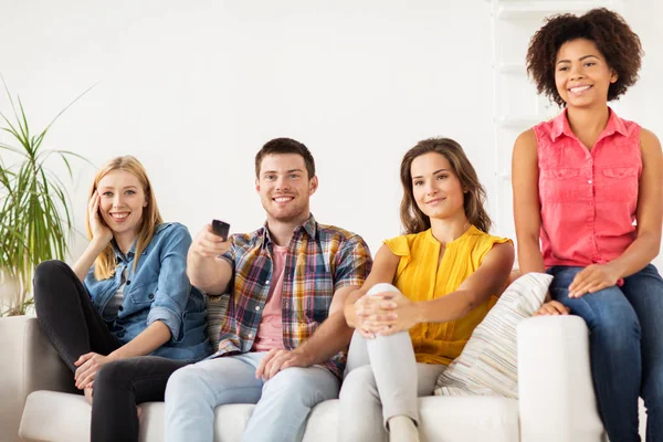 Amigos felices con control remoto viendo la televisión en casa —  Fotos de Stock