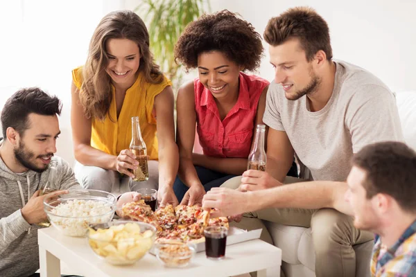 Glada vänner med drycker som äter pizza hemma — Stockfoto