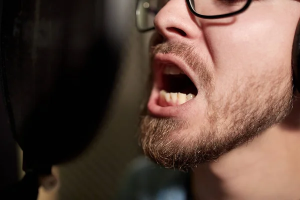 Homem com fones de ouvido cantando no estúdio de gravação — Fotografia de Stock