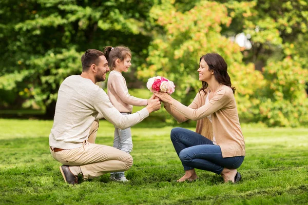 Happy family with flowers in summer park — Stock Photo, Image