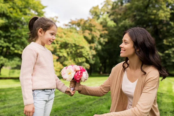 Chica dando con flores a la madre en el parque de verano —  Fotos de Stock