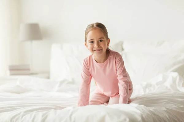Ευτυχισμένη κοριτσάκι στο κρεβάτι στο σπίτι υπνοδωμάτιο — Φωτογραφία Αρχείου