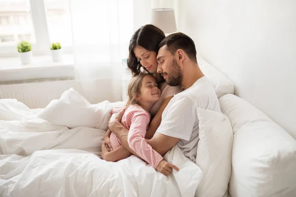 Gelukkige familie knuffelen in bed thuis — Stockfoto