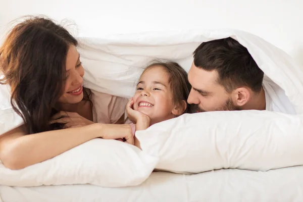 Heureux famille couché dans le lit sous couverture à la maison — Photo