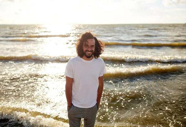 Homem feliz em t-shirt branca na praia sobre o mar Fotos De Bancos De Imagens Sem Royalties