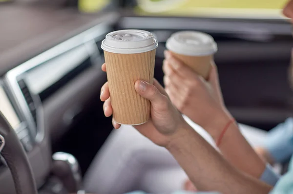 Закрытие пары, едущей в машине с чашками кофе — стоковое фото