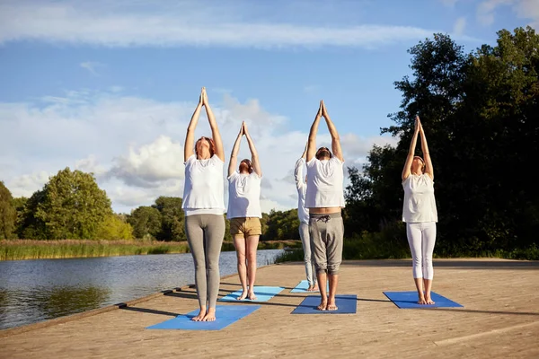 Grupo de personas haciendo ejercicios de yoga al aire libre —  Fotos de Stock